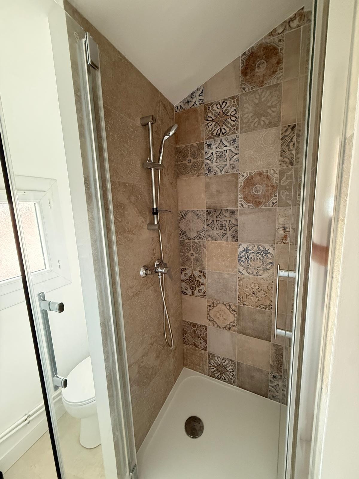 La salle d’eau avec sa douche à l’italienne et son carrelage à motifs La salle d’eau avec sa douche à l’italienne et son carrelage à motifs