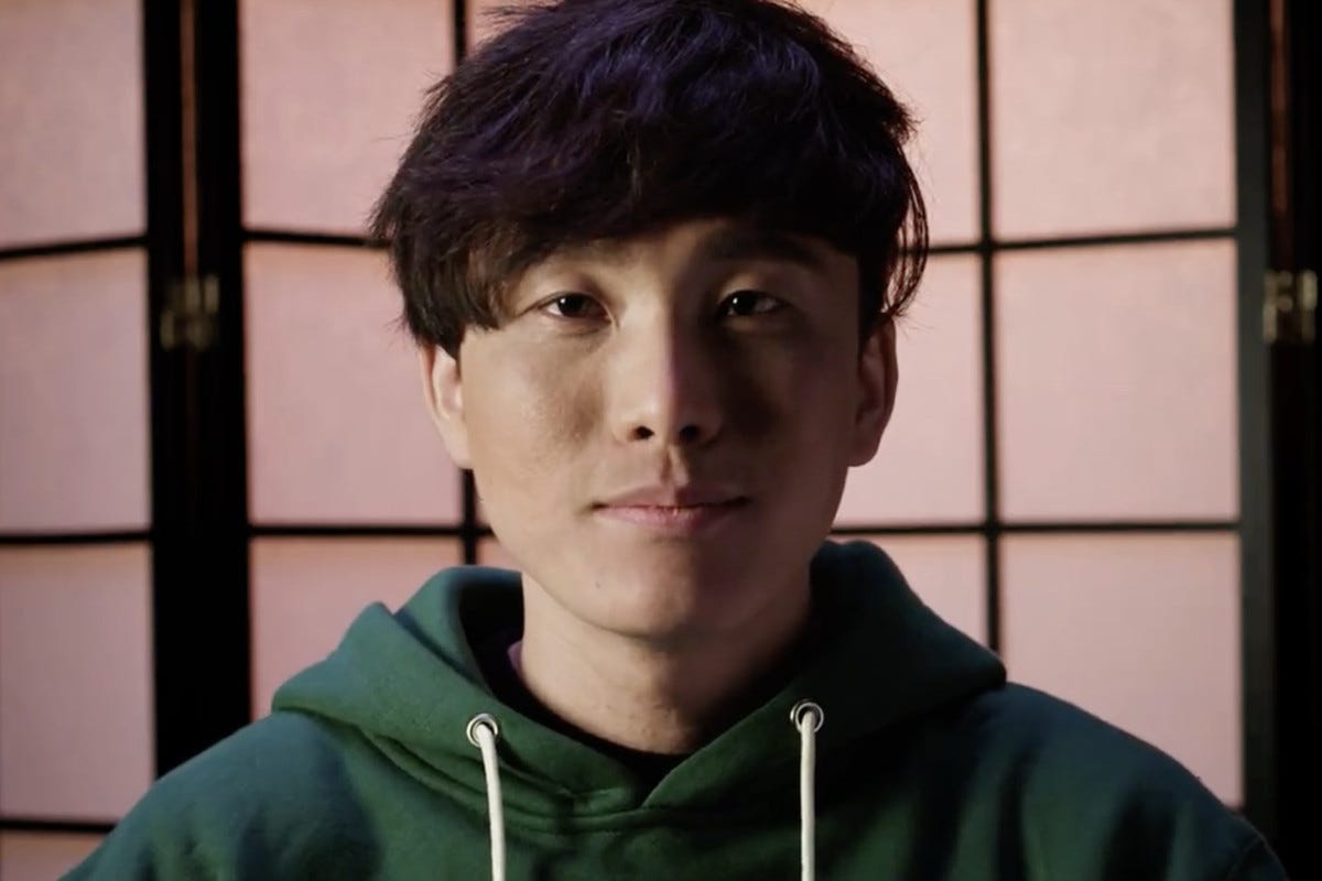 a man staring at the camera, a screen behind him