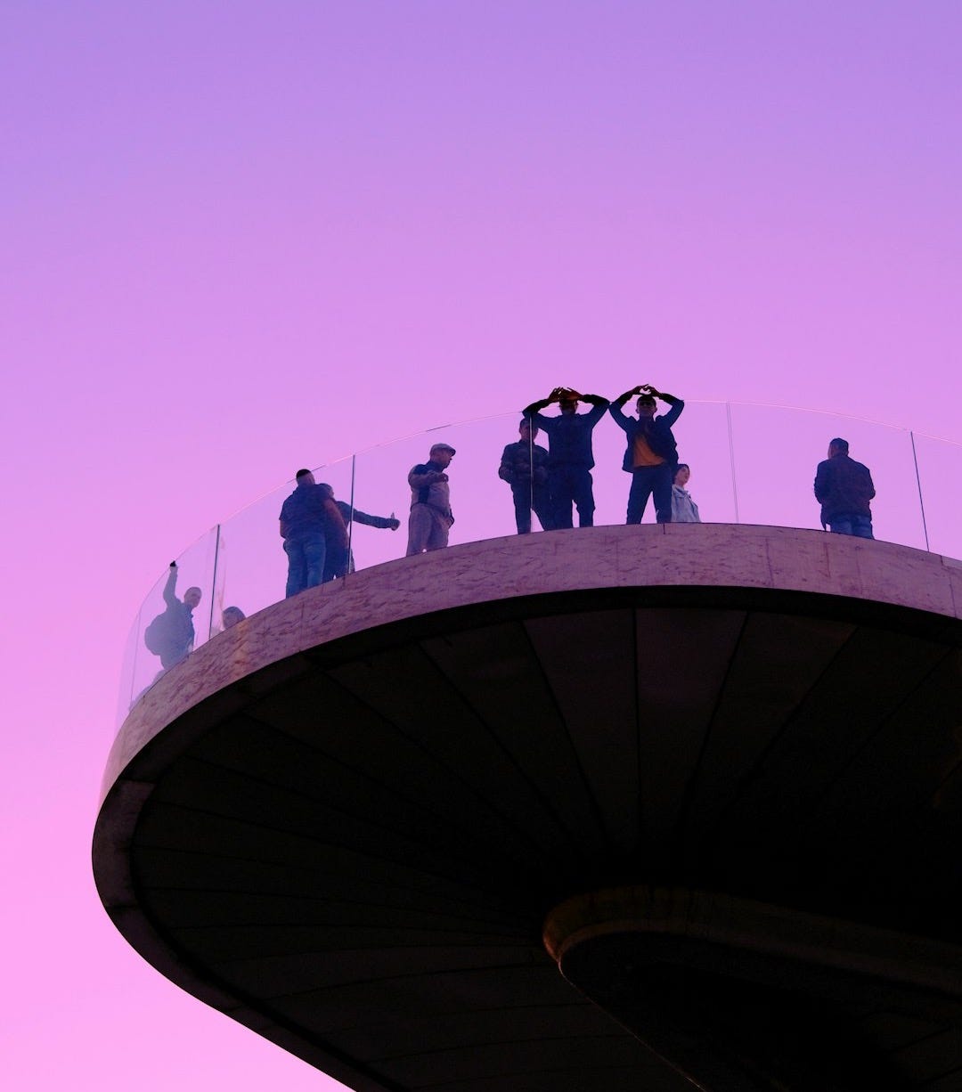 a group of people standing on top of a tall building a group of people standing on top of a tall building