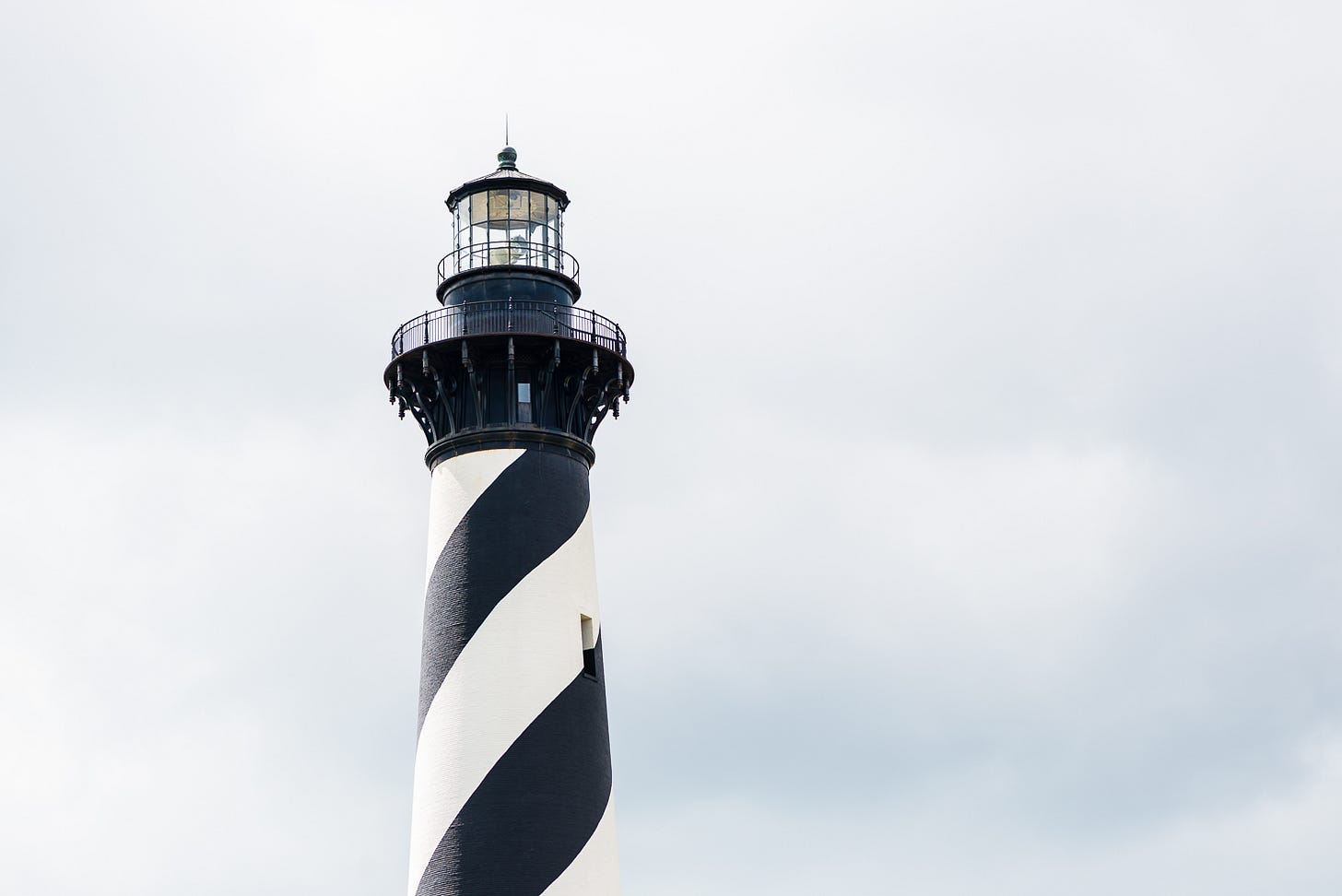 Close up of the top of a lighthouse with black and white swirling stripes.