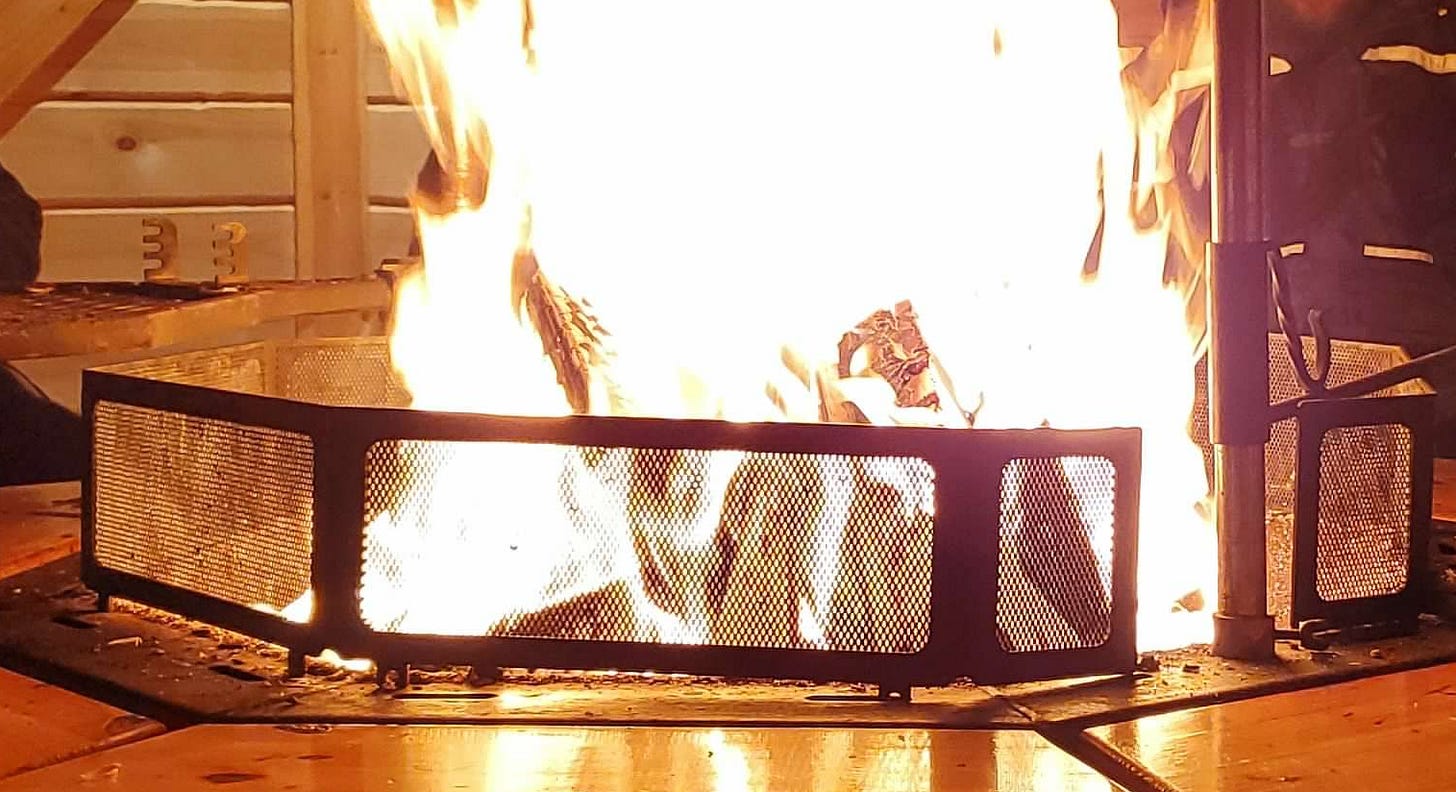 a large fire burns in a metal grate