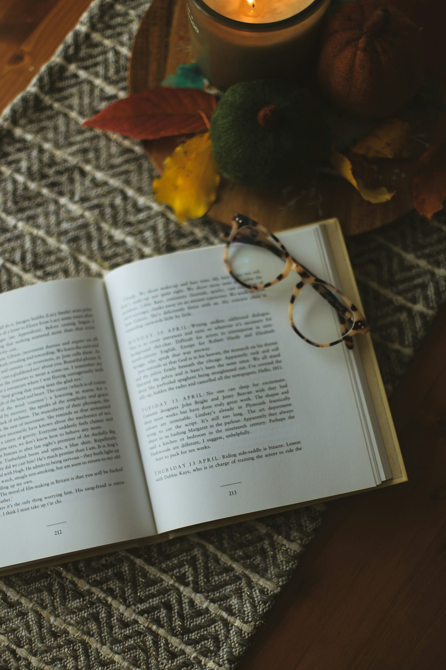open book on a rug with folded glasses resting on the open page.