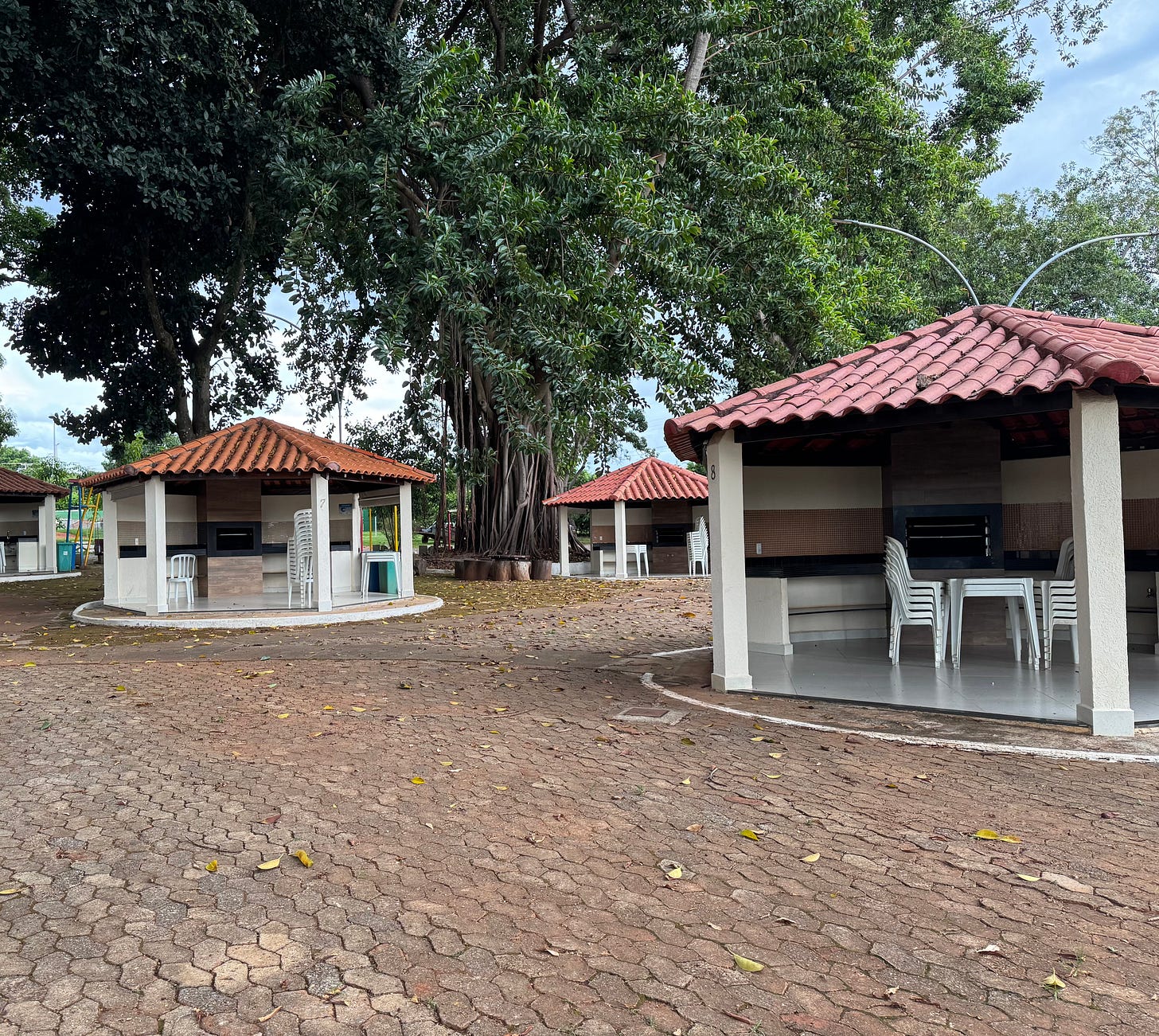 Churrasco pavilions under tall trees.