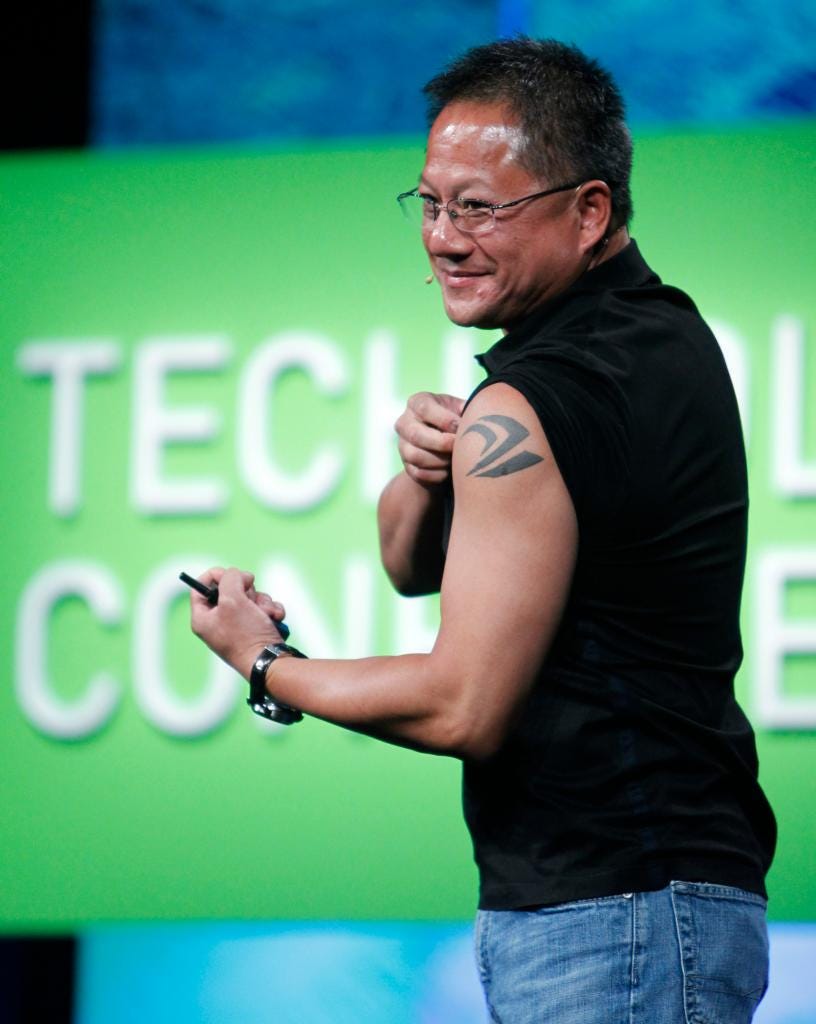 Jen-Hsun Huang, wearing glasses and a black shirt, displaying a tattoo during his keynote address in San Jose at the GPU Technology Conference.