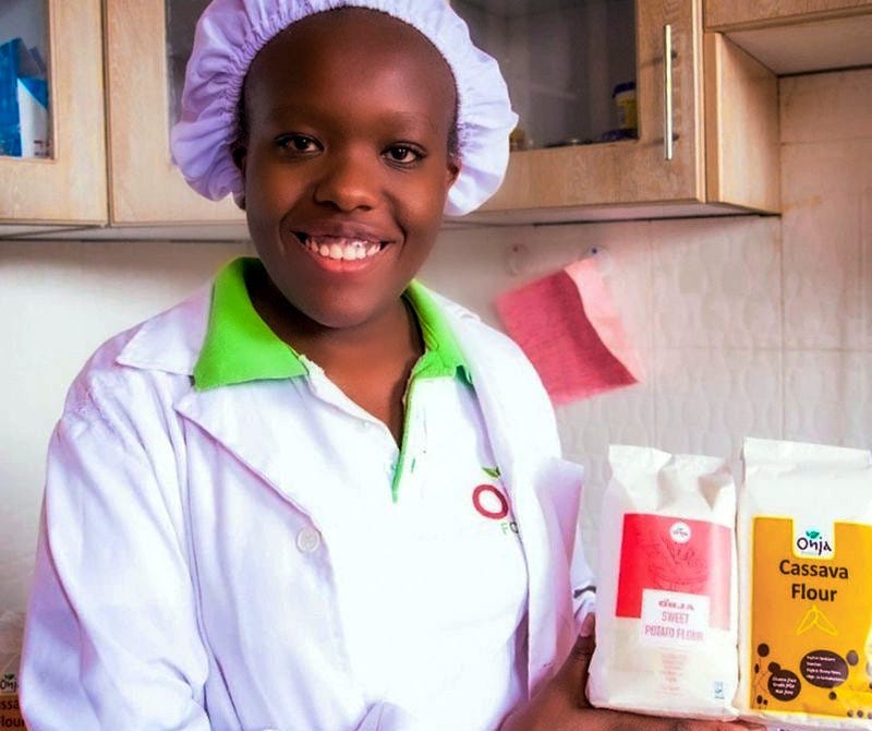 Mary Karoki, founder of Onja Foods, posing for a picture with packets of her company's flour. 