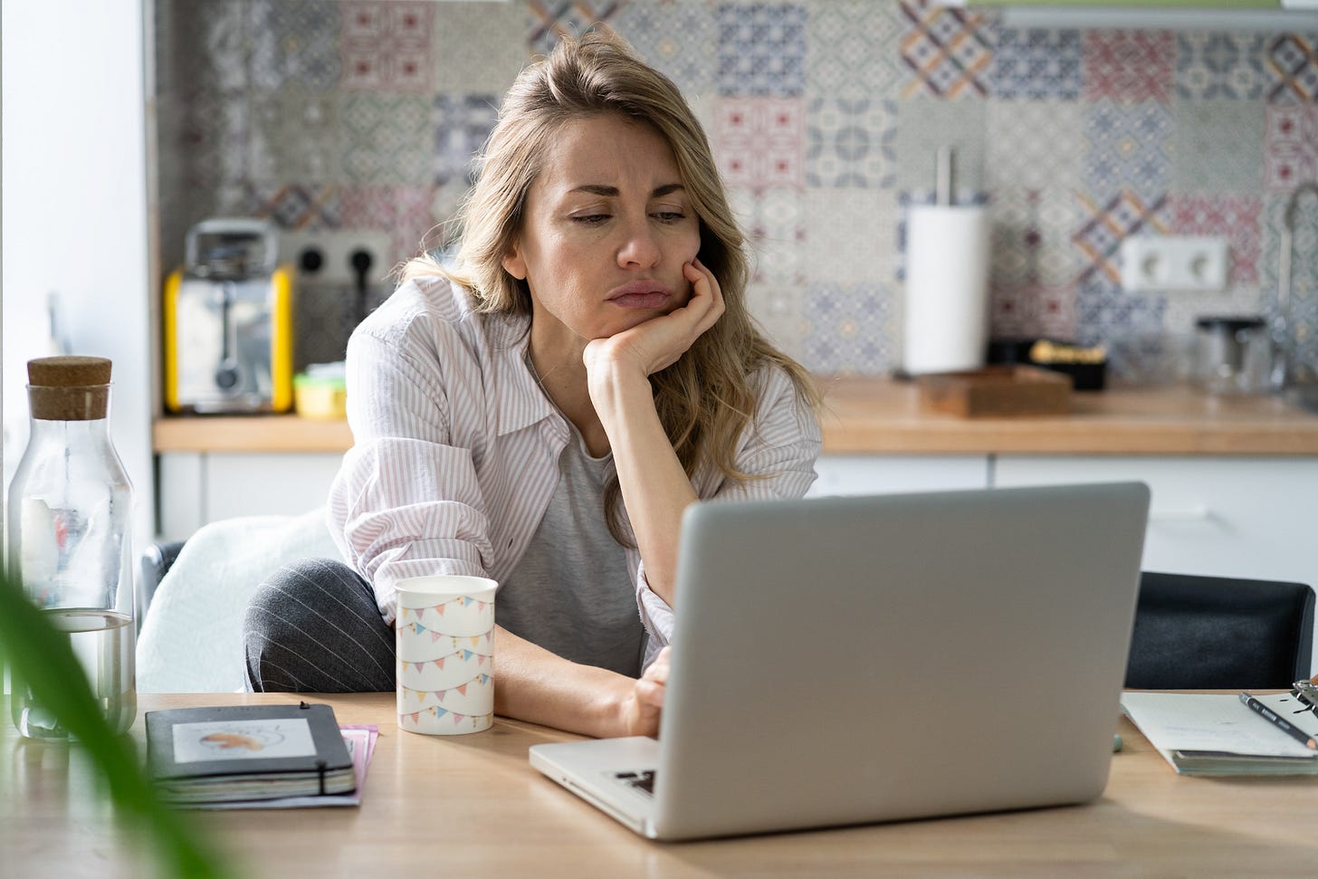 Stressed job seeker looking at her laptop in her kitchen