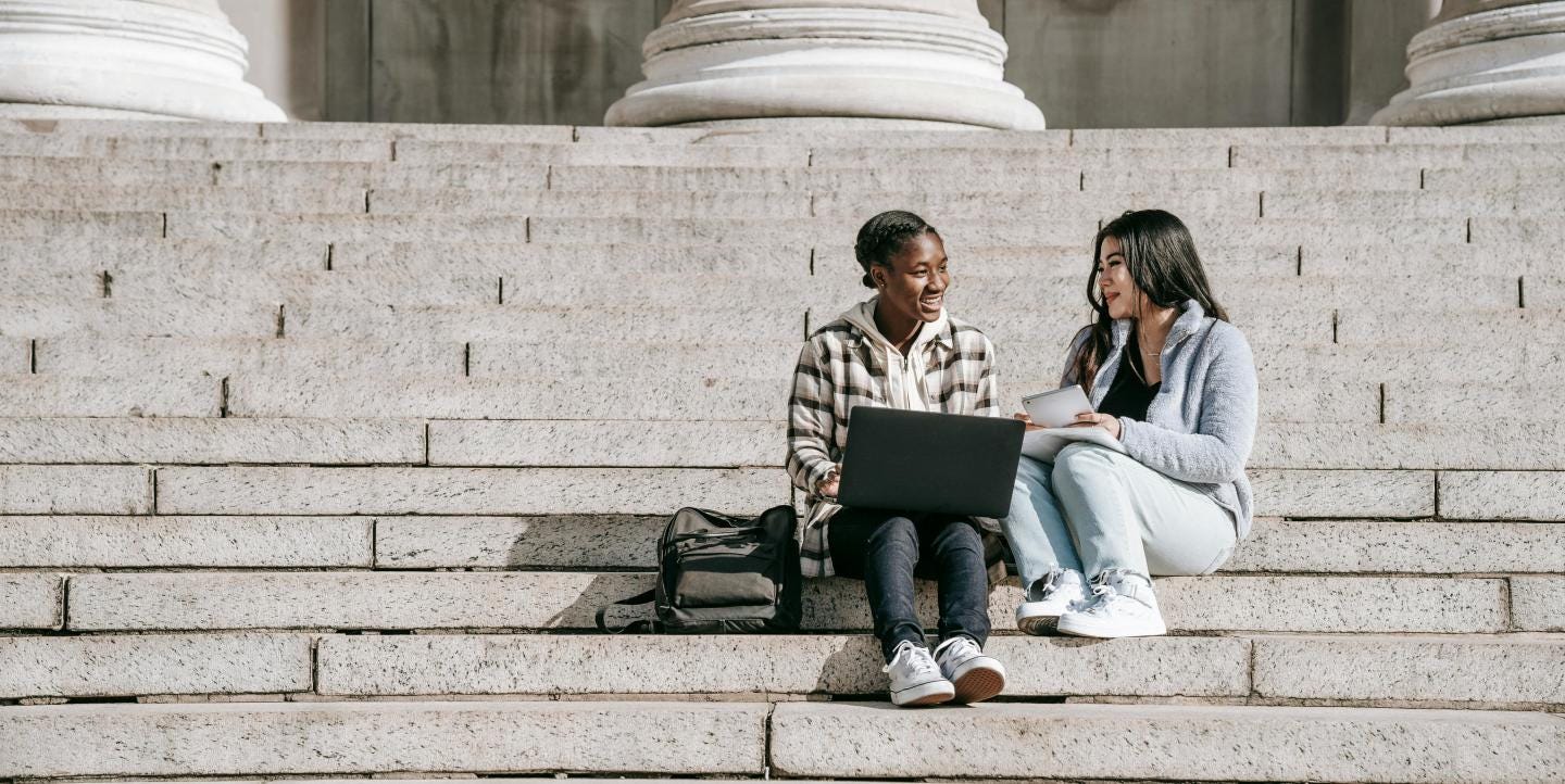Two students sitting on outside steps. 