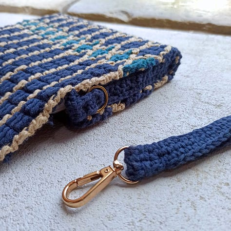 Overlay mosaic crochet wristlet bag with geometric pattern in blues and beige.