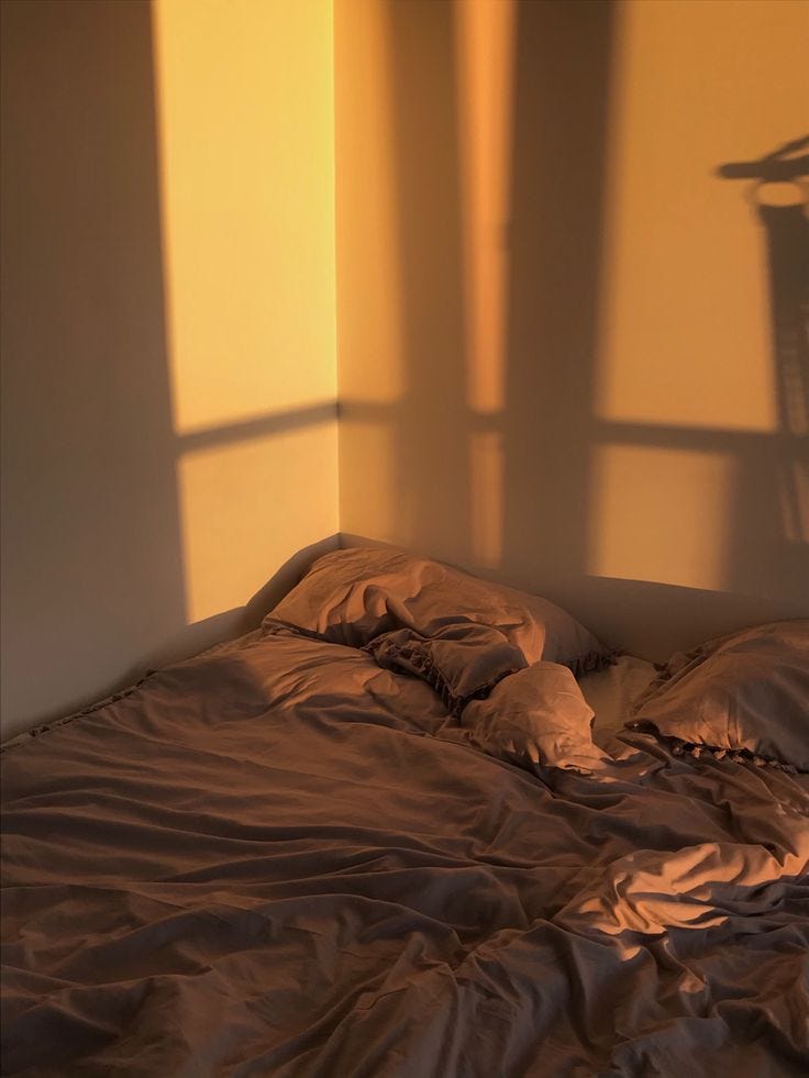 This may contain: an unmade bed in the corner of a room with sunlight coming through the window
