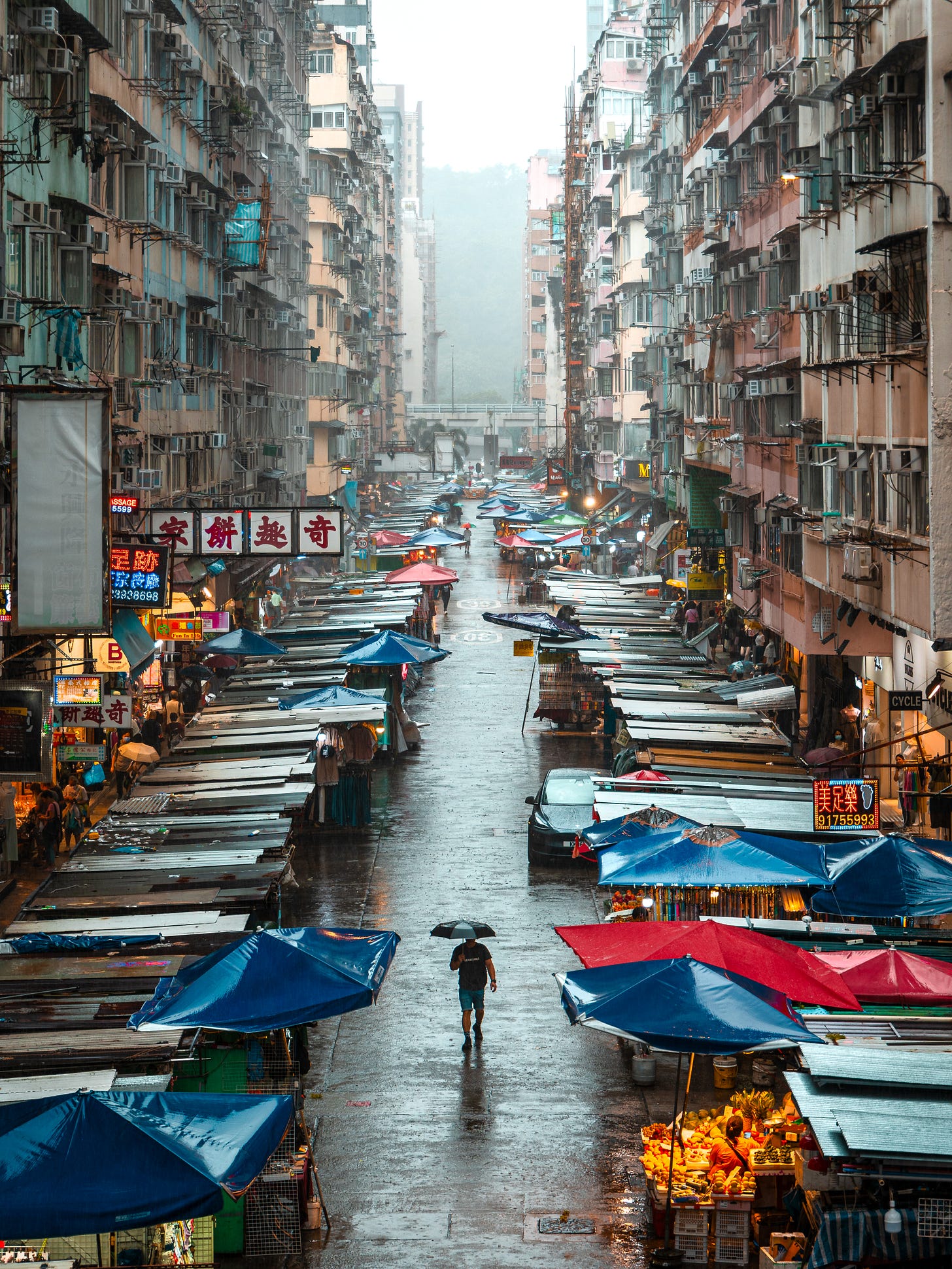 Fa Yuen Street market in Mong Kok, Hong Kong, seen from above on an overcast day with a lone figure carrying an umbrella Fa Yuen Street market in Mong Kok, Hong Kong, seen from above on an overcast day with a lone figure carrying an umbrella