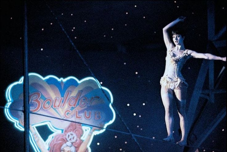 Nastassja Kinski walks a tightrope in front of a neon sign reading "Boulder Club" against the star-filled night sky in One from the Heart. Nastassja Kinski walks a tightrope in front of a neon sign reading "Boulder Club" against the star-filled night sky in One from the Heart.