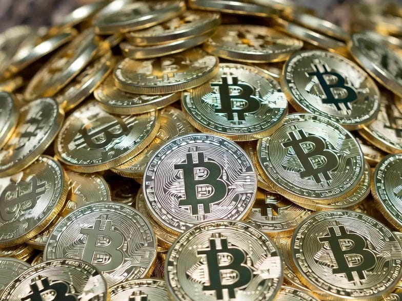 A photograph of a chaotic pile of physical Bitcoin coins in an outdoor setting. A photograph of a chaotic pile of physical Bitcoin coins in an outdoor setting.