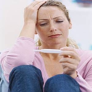 Photo of a woman looking at a home pregnancy test and appearing to be upset Photo of a woman looking at a home pregnancy test and appearing to be upset