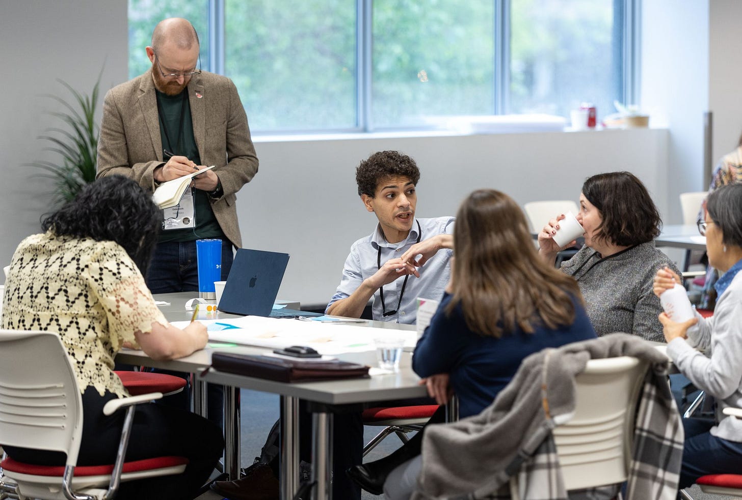 An image of the author standing and taking notes and other participants talking at the Forum for Social Innovation