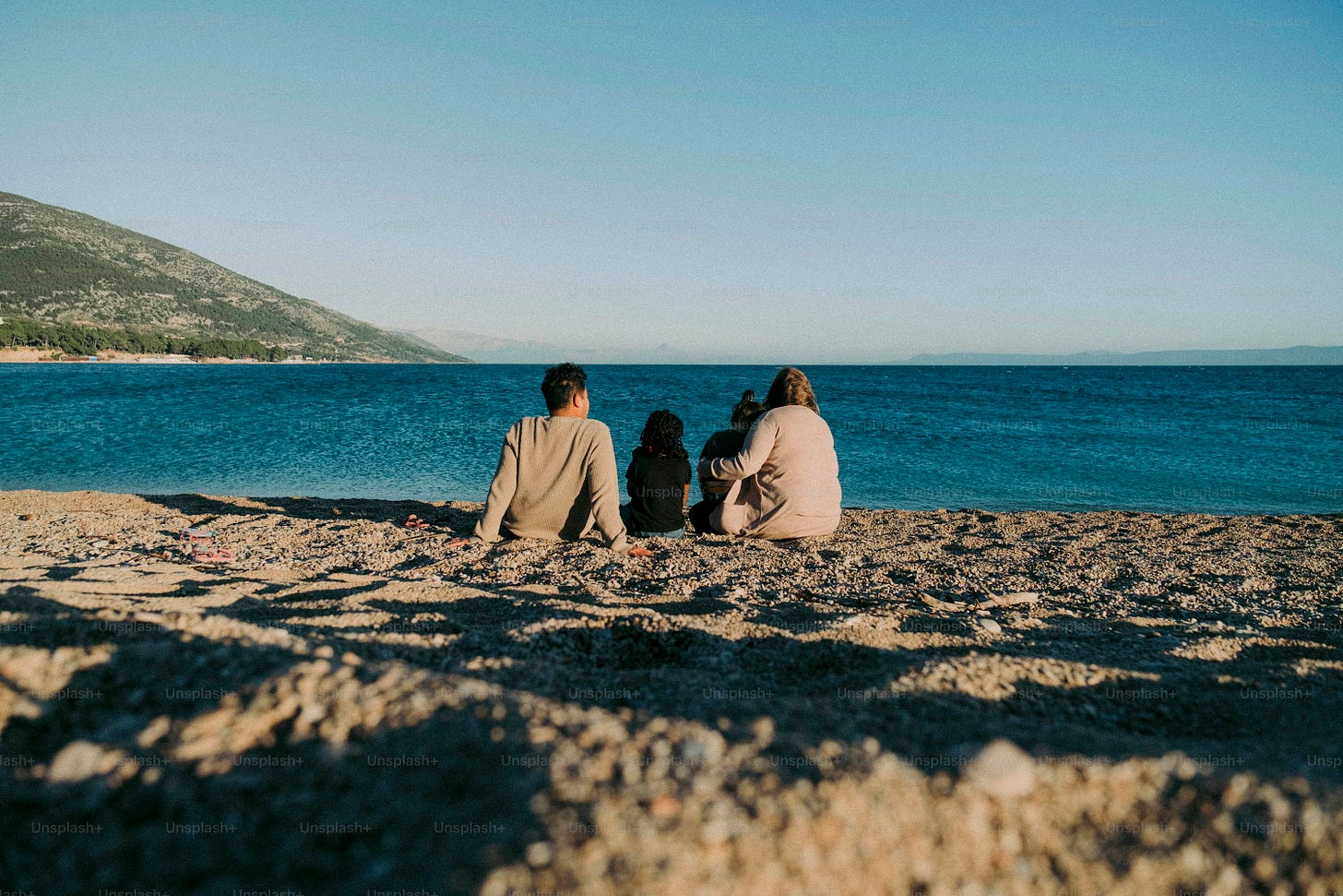 a couple of people sitting on top of a sandy beach a couple of people sitting on top of a sandy beach