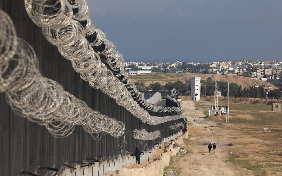 Displaced Palestinians walk next to the border fence between Gaza and Egypt, on February 16, 2024, in Rafah, in the southern Gaza Strip, amid the ongoing war between Israel and the Hamas terror group. (Mohammed Abed/AFP)