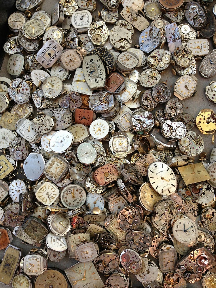 A large collection of watches and clocks on the sand. A large collection of watches and clocks on the sand.