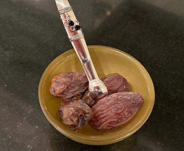 Four plump Medjool dates nestle in a gold glass bowl.