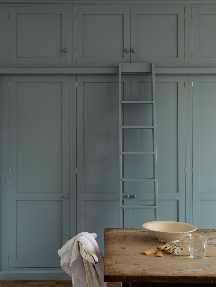 This may contain: an image of a dining room with blue walls and wooden table in the foreground