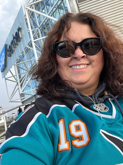 Photo 1: Image of woman in Sharks jersey smiling outside arena; Photo 2: Image of Joe Thornton ice sculpture; Photo 3: Image of Joe Thornton coming through Shark head on ice; Photo 4: image of two women smiling with ice rink behind them; Photo 5: Image of Shark head and chairs on ice for ceremony; Photo 6: Image of Joe Thornton on big screen; Photo 7: Image of Thank You Joe box where jersey was raised with family behind it; Photo 8: Image of ice rink with Shark head and players; Photo 9: Image of #12 and #19 jersey's hanging in the rafters of the arena