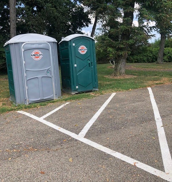The pair of port-o-johns by the parking lot.
