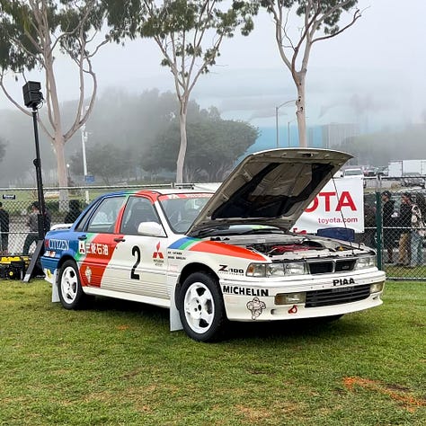A collection of cars at the 2023 Japanese Classic Car Show on a cloudy day in Long Beach, California.
