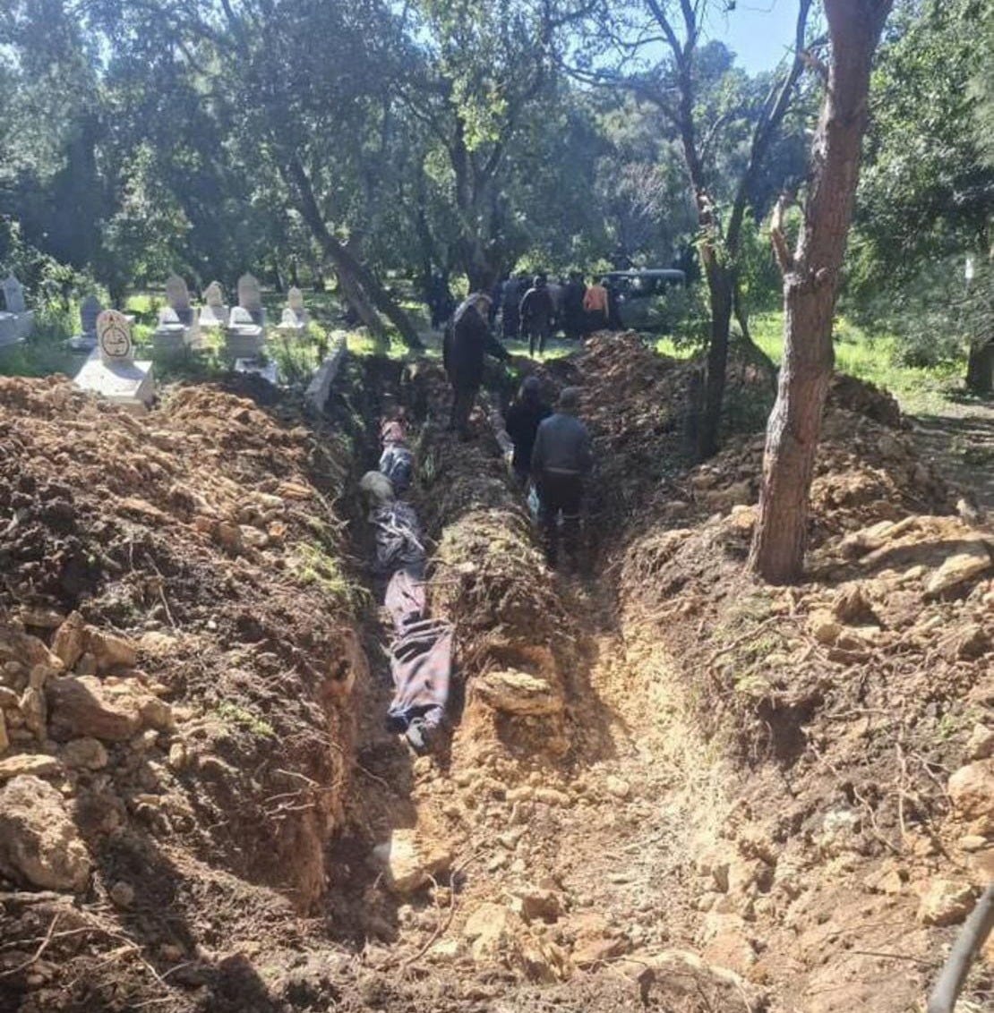 Bodies are laid in a mass grave in Pine village.