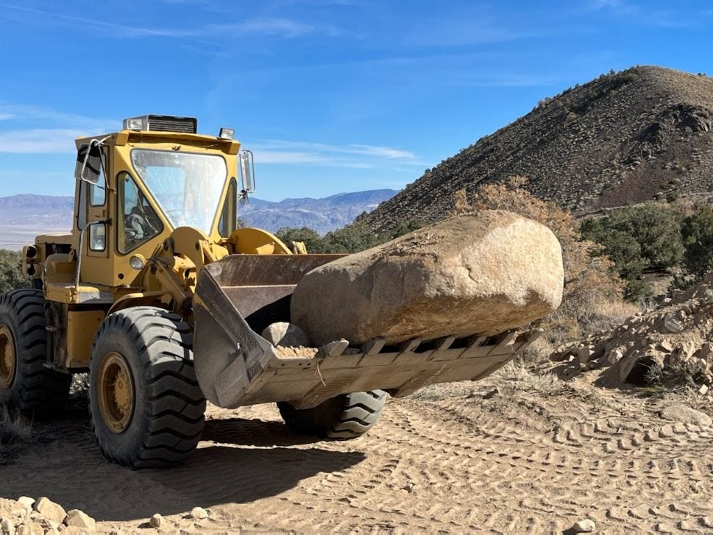 Frontloader with a large rock in its bucket.
