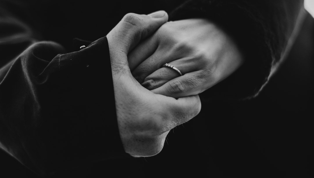 grayscale photo of man and woman kissing while holding hands