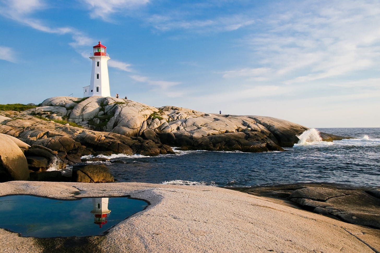 A lighthouse perched on some rocks by the sea