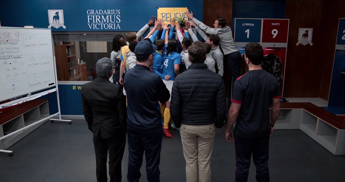 The entire AFC Richmond team touching the Believe Sign in Ted Lasso