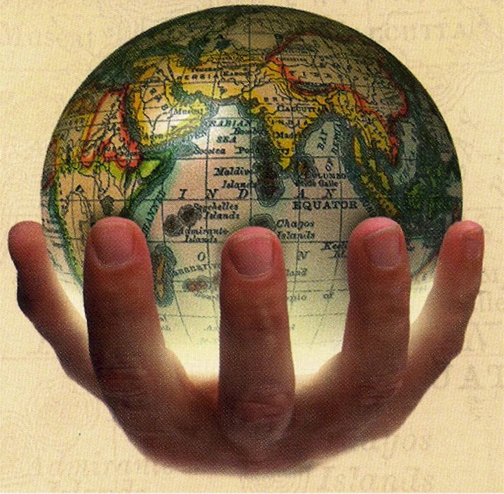 This may contain: a person's hand holding up a small globe in front of a beige background This may contain: a person's hand holding up a small globe in front of a beige background
