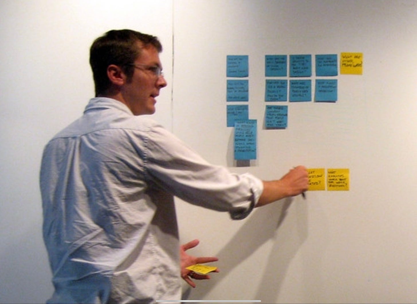 Guy placing sticky notes on a whiteboard Guy placing sticky notes on a whiteboard