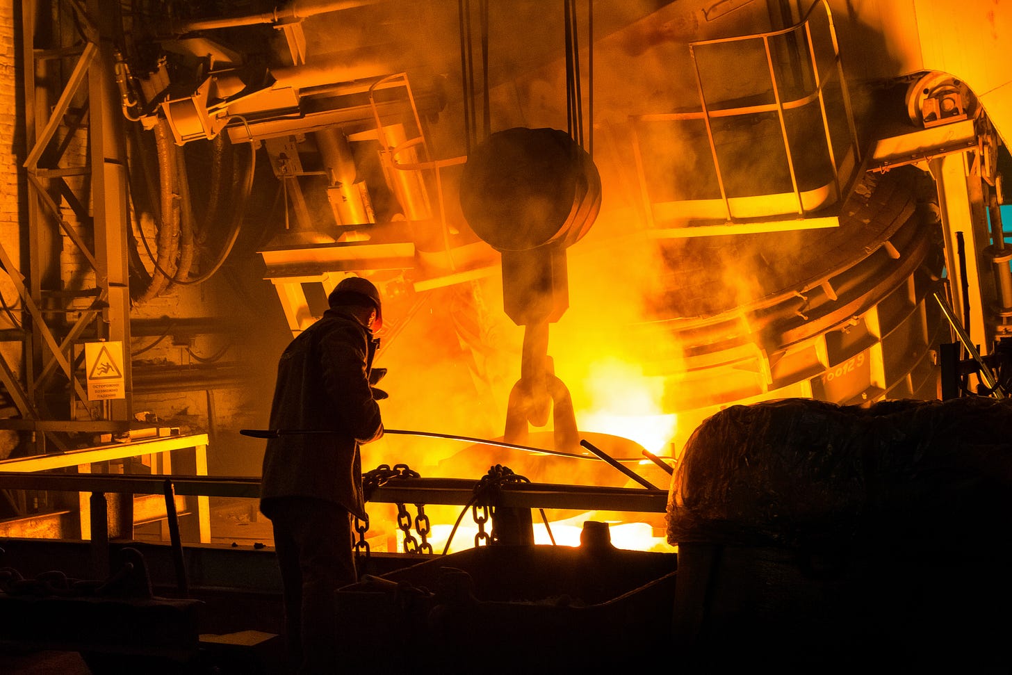 A man operates an industrial forge.