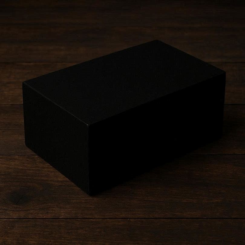 On a wooden table, there was a large black brick, about the size of a box for work boots, as dark as the night and seemingly drawing the light from around it. It wasn’t shiny, it wasn’t dull. It just… was... black.
