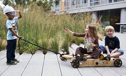 Three children on the walkway in New York City's High Line park. One pulls a makeshift wagon with one of the kit's cords; two others ride the wheeled structure they've built. Three children on the walkway in New York City's High Line park. One pulls a makeshift wagon with one of the kit's cords; two others ride the wheeled structure they've built.