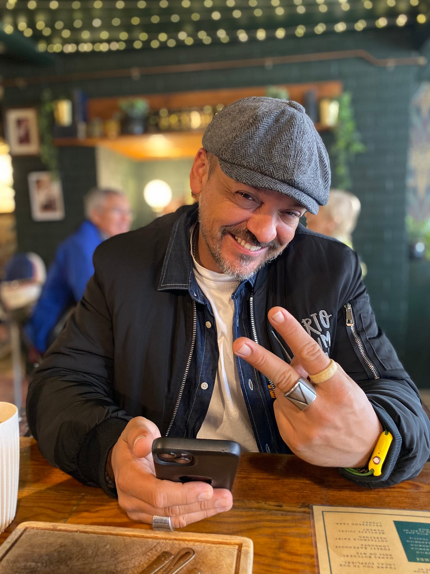 A smiling Hugo Danin wearing a cap and joking with a hand gesture