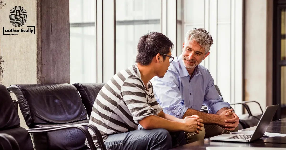 Younger and older man sitting discussing an issue in front of a laptop