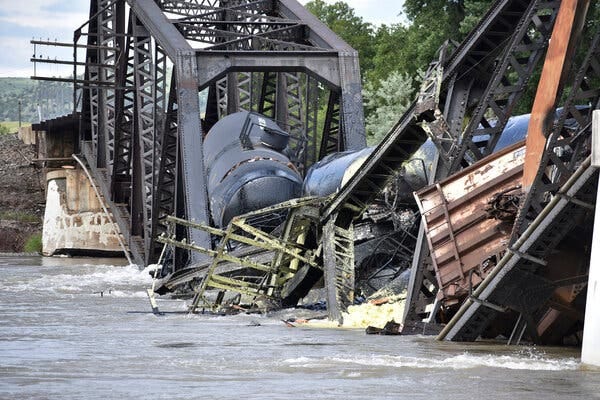 Derailed tanker cars and the twisted metal of a collapsed bridge fallen in the Yellowstone River.