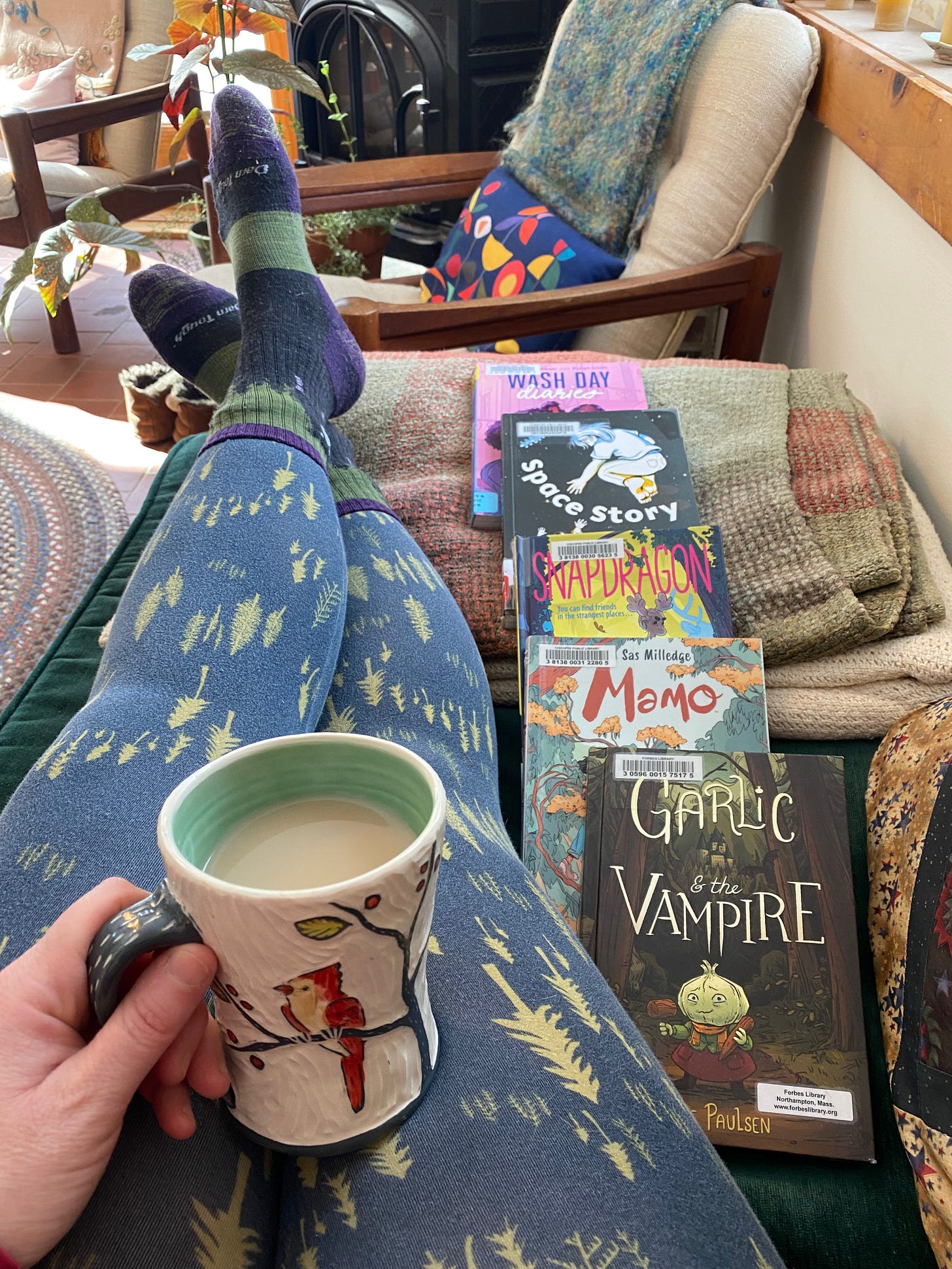 My legs stretched out on a chaise, next to a stack of graphic novels, including the two mentioned.