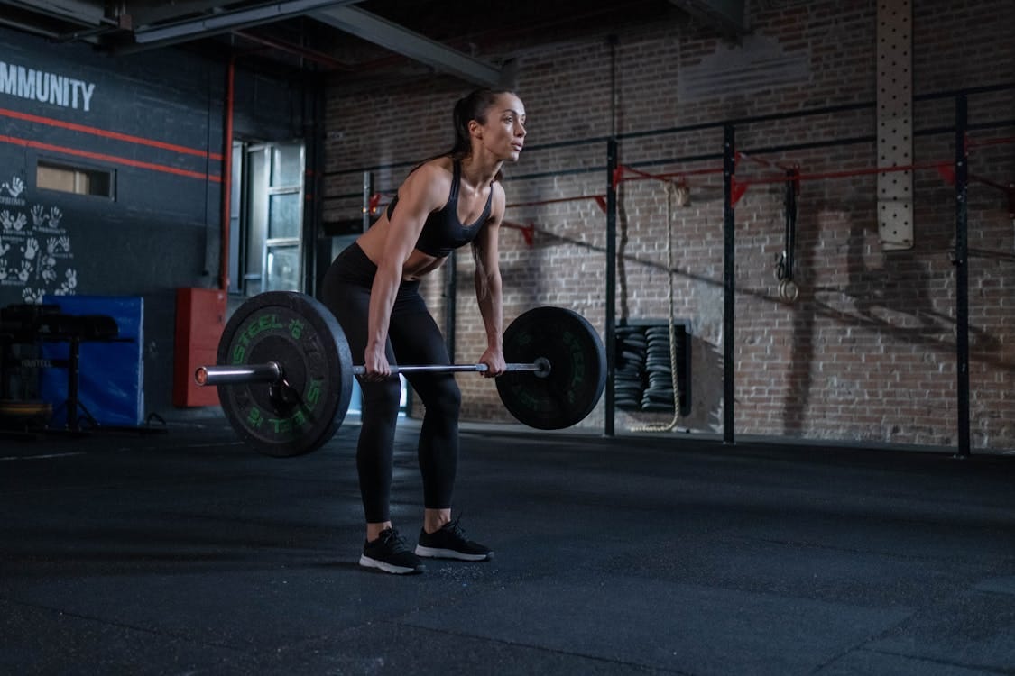 Free A determined woman performing deadlifts in a modern gym environment, showcasing strength and fitness. Stock Photo Free A determined woman performing deadlifts in a modern gym environment, showcasing strength and fitness. Stock Photo