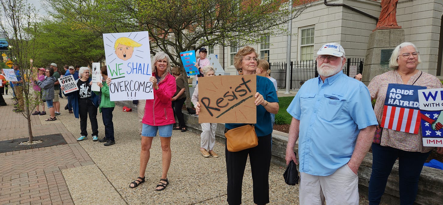 People on a sidewalk holding protest signs.