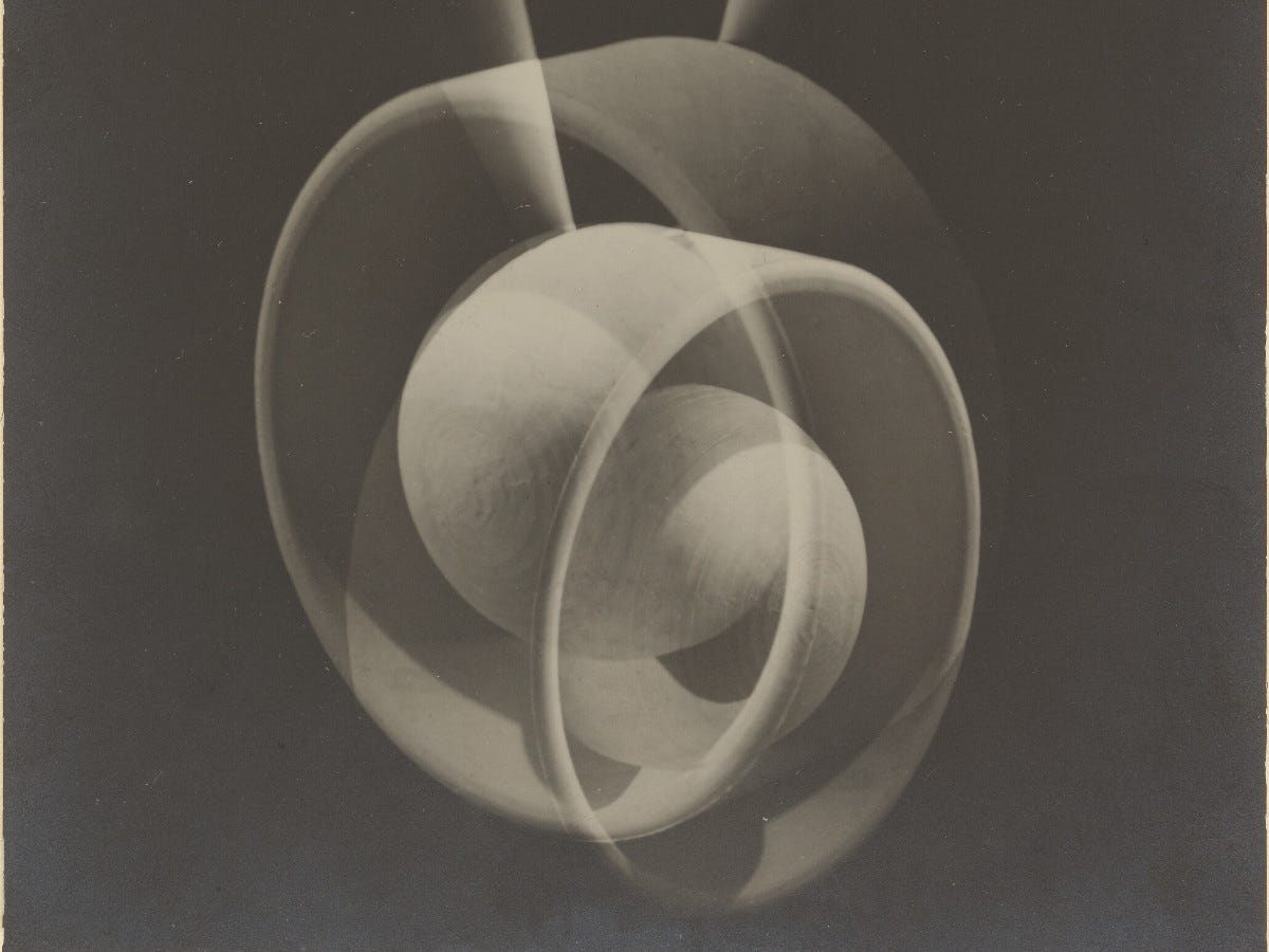 Abstract form featuring a sphere in the center of two intersecting rings on black background. Abstract form featuring a sphere in the center of two intersecting rings on black background.