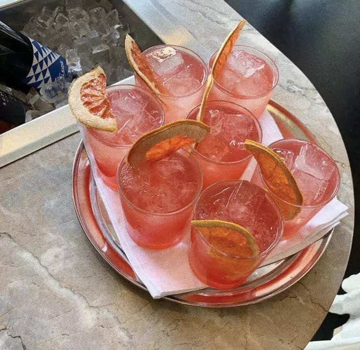 This may contain: there are many glasses on the plate with orange slices
