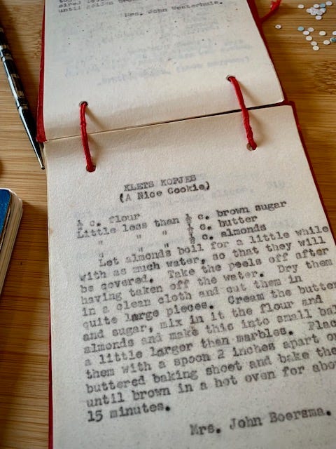 two books on a table, one is an old recipe collection, the other is a new notebook with blank pages