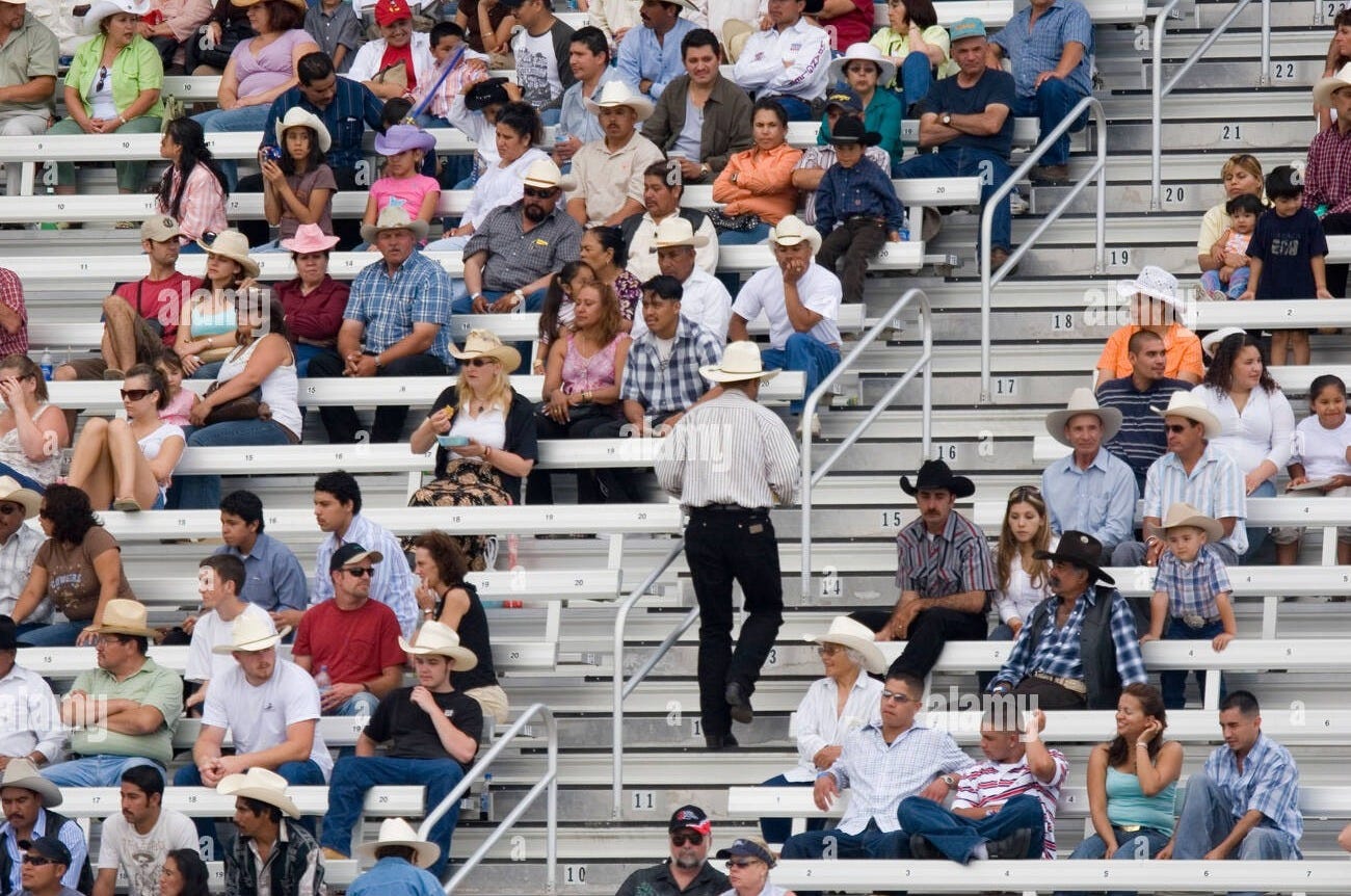 Rodeo crowd sitting in stadium bleacher seats with man in a cowboy hat walking up the aisle Stock Photo - Alamy Rodeo crowd sitting in stadium bleacher seats with man in a cowboy hat walking up the aisle Stock Photo - Alamy