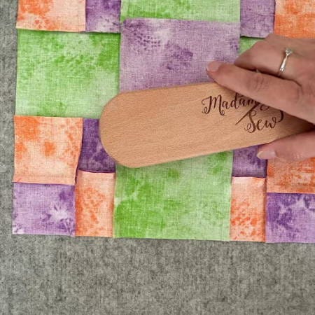 using a wooden clapper on a quilt block