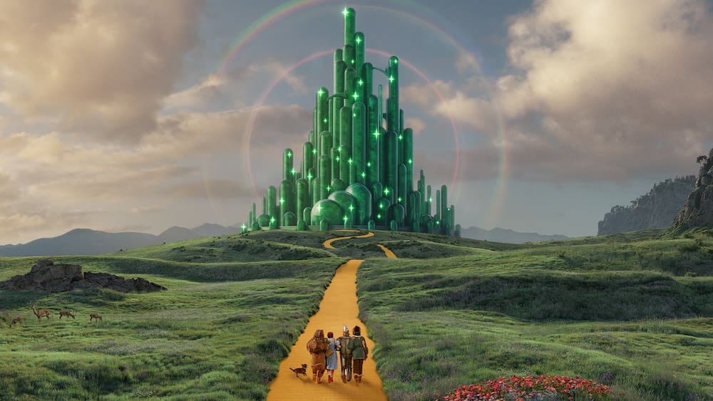 Dorothy and her companions walk down the yellow brick road towards the Emerald City in the distance