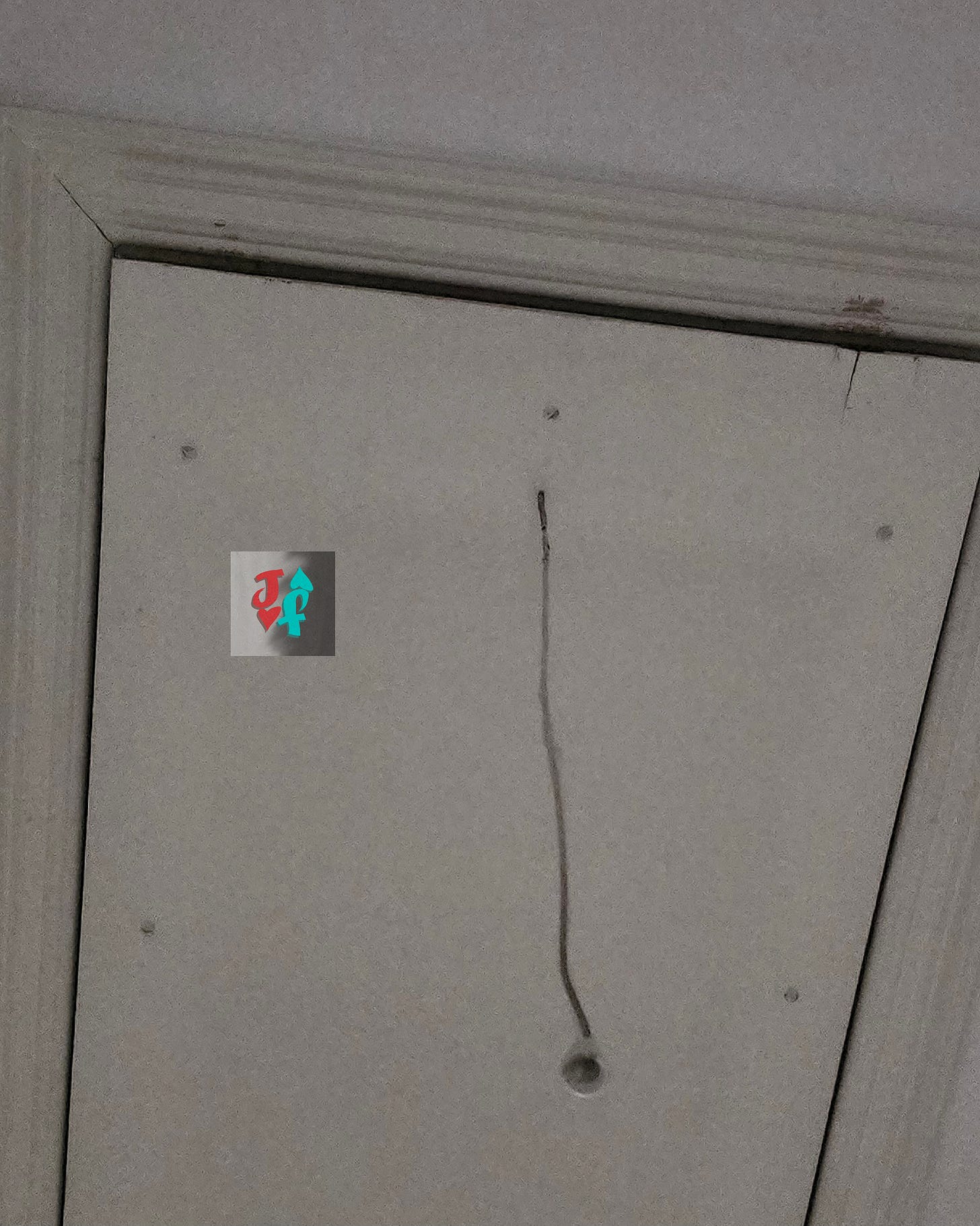 A photo of an attic door taken from below at daytime. A photo of an attic door taken from below at daytime.
