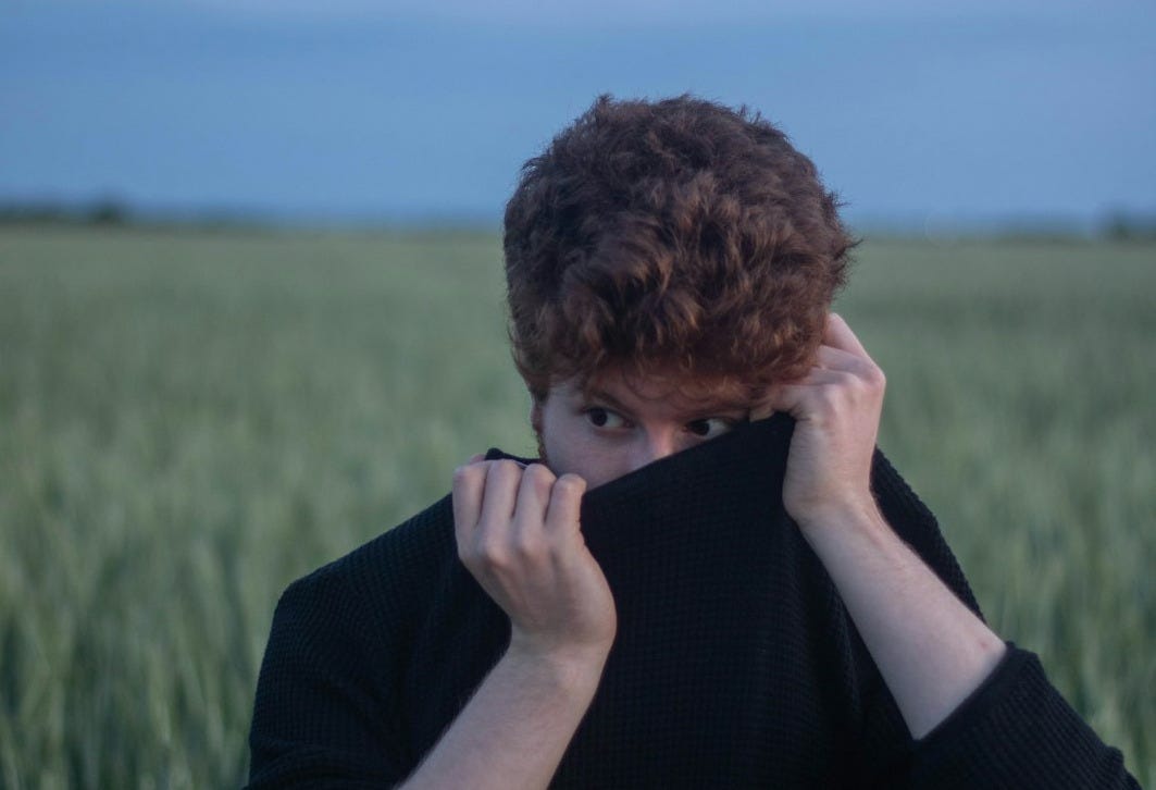 man in black long sleeve shirt covering his face with his hand